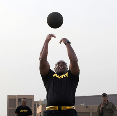 Army man throwing medicine ball in the air to train arms